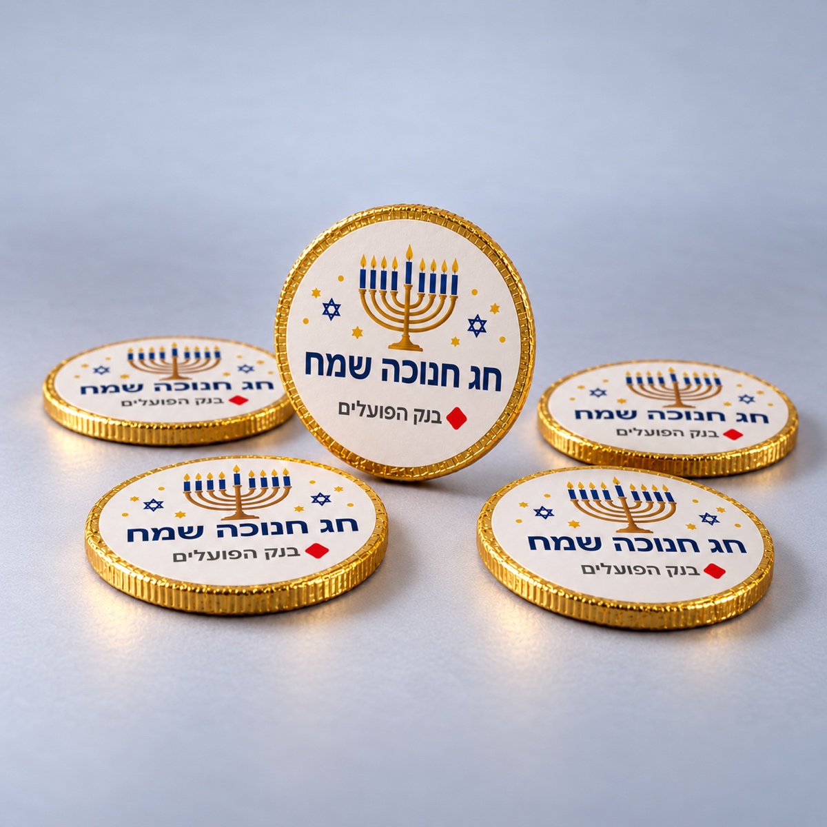 מטבעות שוקולד ממותגים לחנוכה – דוגמת מיתוג מטבעות שוקולד לחנוכה בעטיפת זהב עם מדבקה ממותגת חג חנוכה שמח ולוגו בנק הפועלים – דוגמת מיתוג